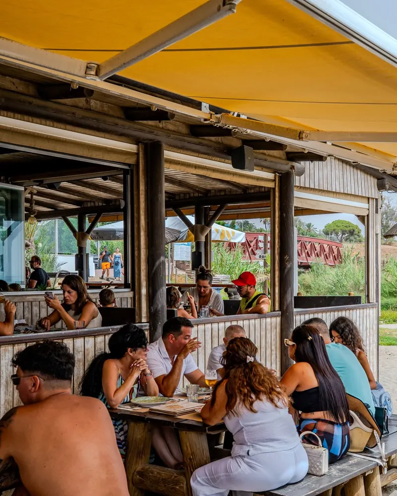 Friends sharing lunch at long wooden tables on the covered terrace