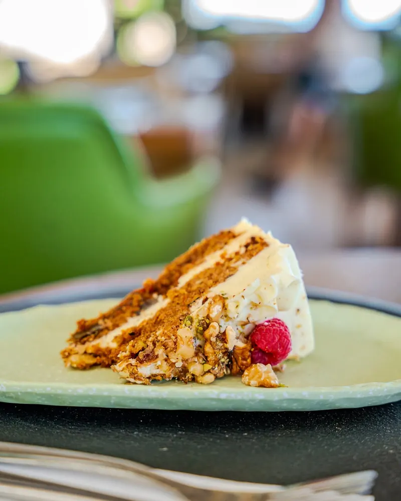 A slice of carrot cake with a raspberry