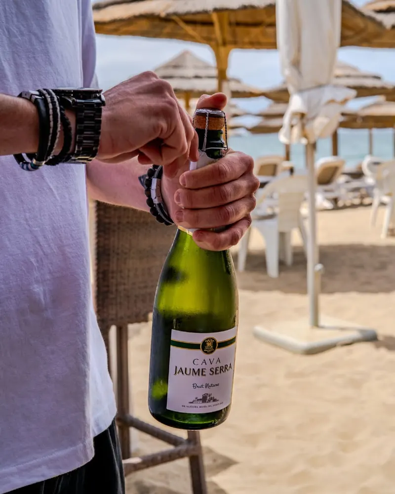 Opening a bottle of cava on the beach