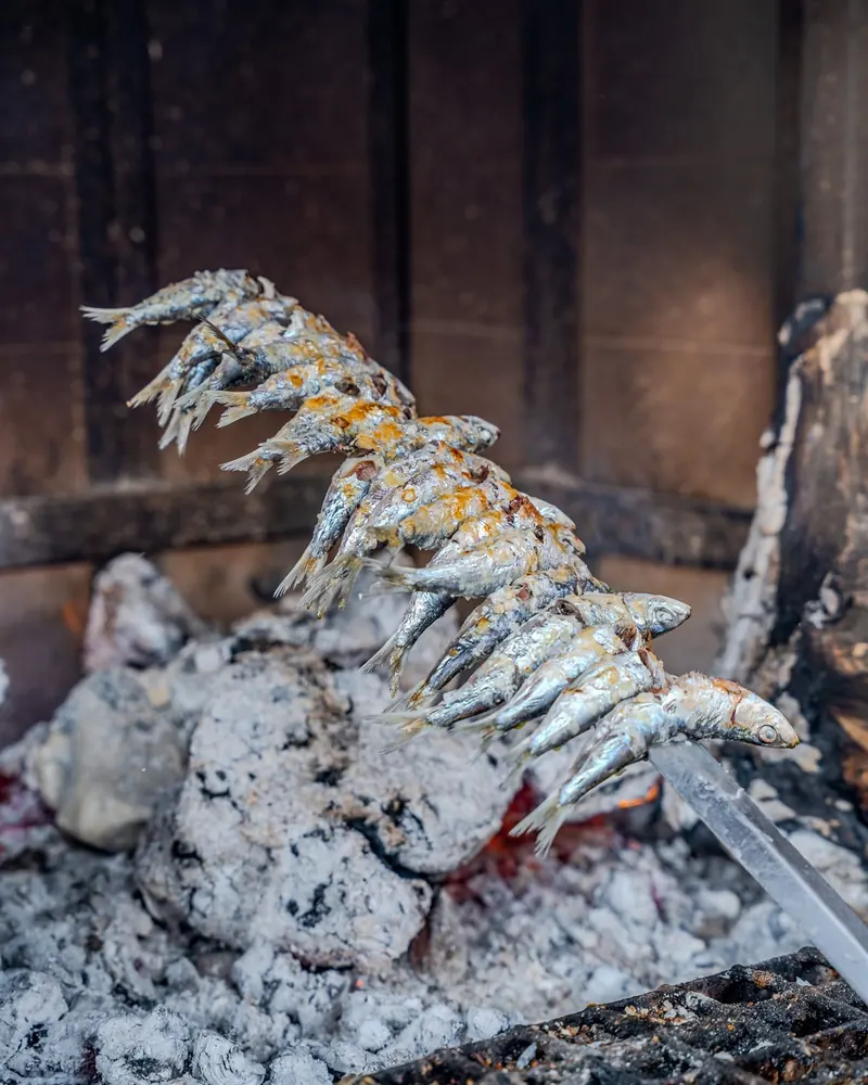 Sardines on a skewer over glowing embers