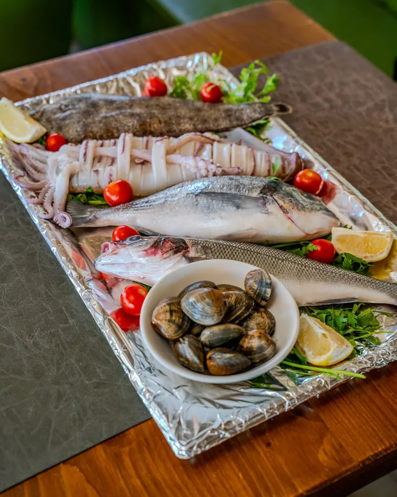 A tray of fresh whole fish, squid and clams with lemon and cherry tomatoes