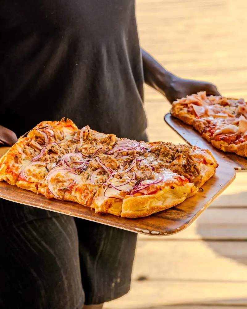 A pizza with tuna and red onion served on a wooden board
