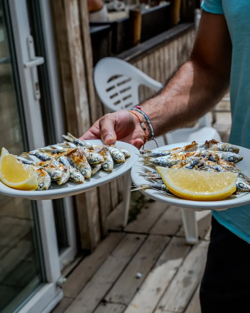 Two plates of grilled sardines with lemon carried out to the terrace